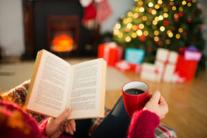 A person reading a book and drinking coffee at Christmas at home in the living room